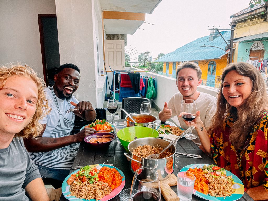 New Friendships! Selfie of Smiling Multi Racial Group of Friends Share a Delicious Peanut Curry Chicken Dish, Salad, Seasoned Rice, and Red Wine for a local Dinner Party Food Tour Experience on a Balcony in Panama City, Panama