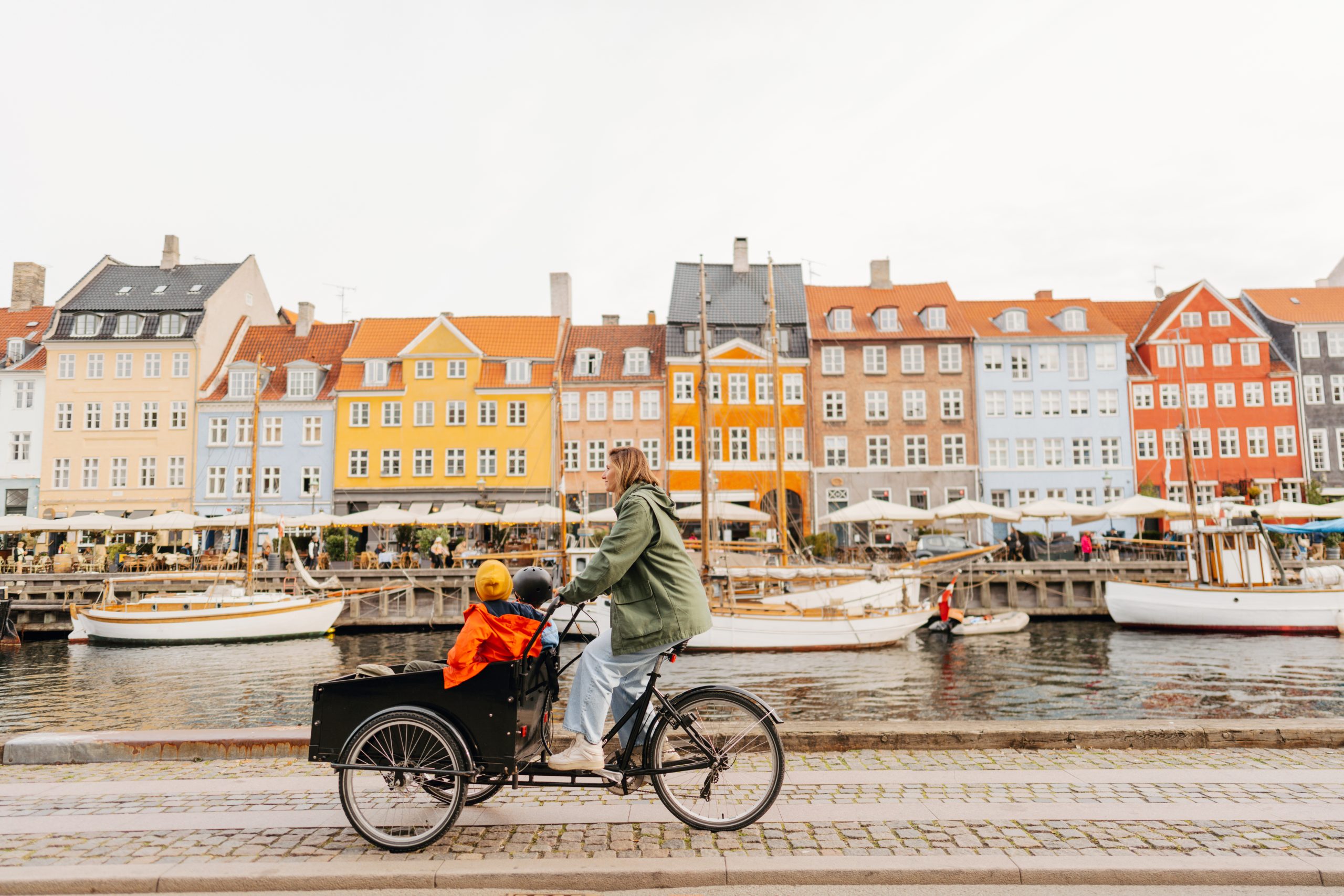 Photo of two boys riding in a cargo bike with their mother in downtown of Copenhagen