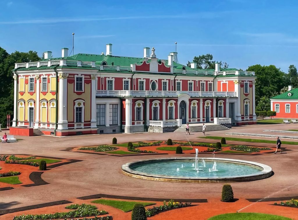 A vibrant view of Kadriorg Palace and Park in Tallinn, Estonia, featuring the grand baroque-style palace surrounded by beautifully manicured gardens and fountains on a sunny day.