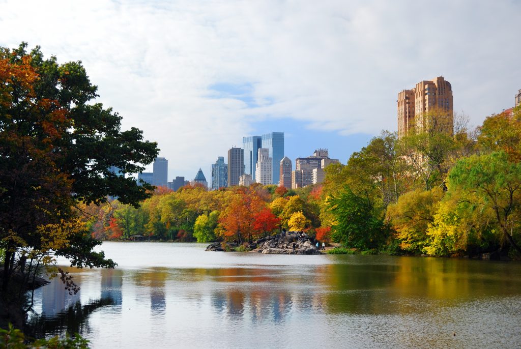 New York City Manhattan Central Park panorama in Autumn lake with skyscrapers and colorful trees with reflection.