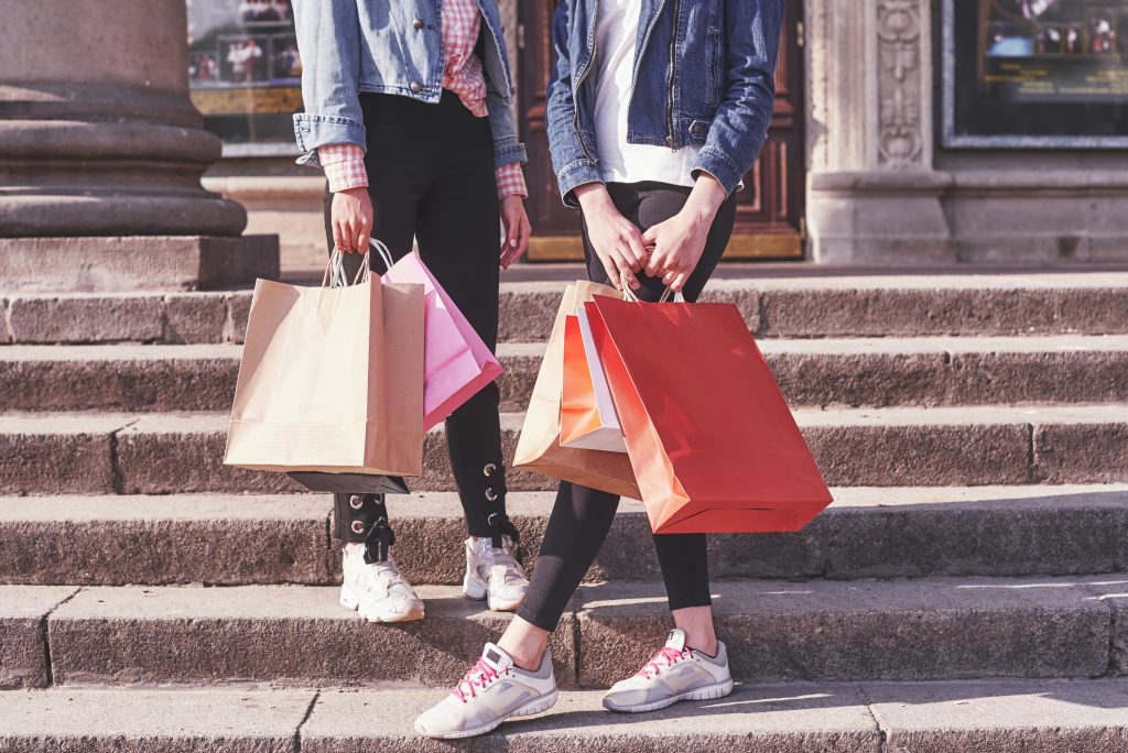 Two young woman carrying shopping bags while walking on the stairs after visiting the stores.